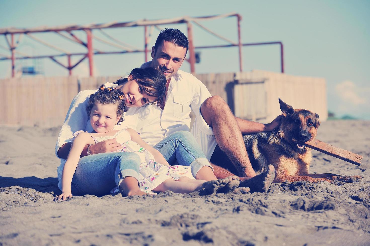 famille heureuse jouant avec un chien sur la plage photo