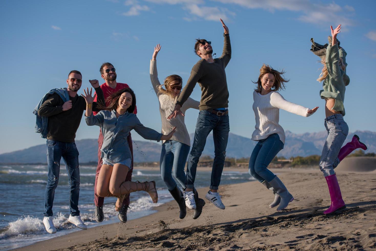 jeunes amis sautant ensemble à la plage d'automne photo