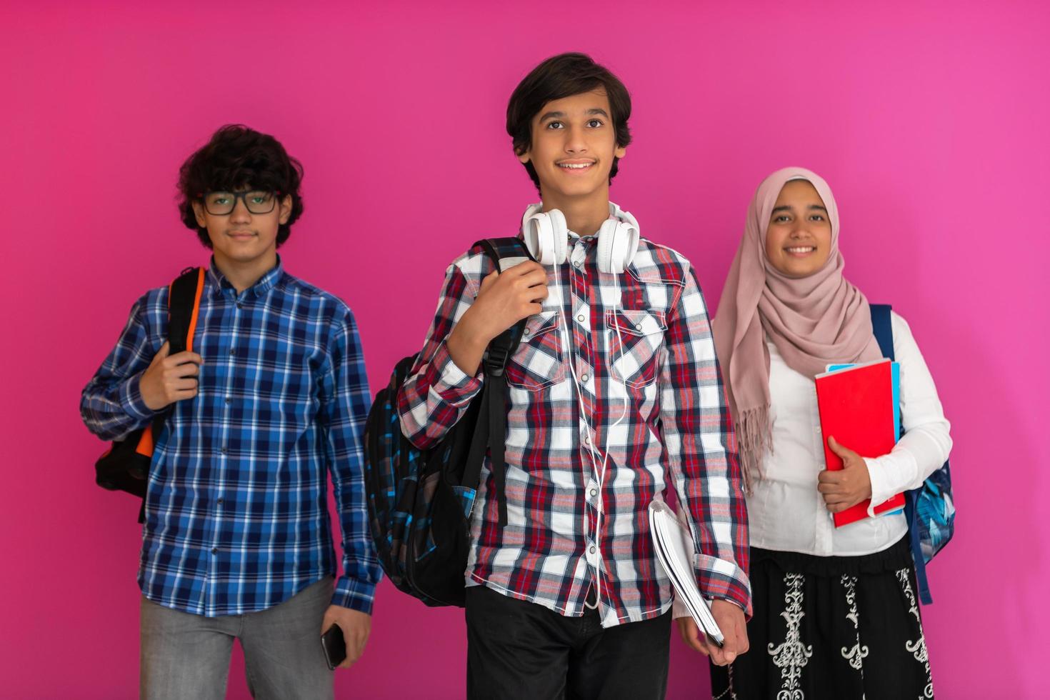 un groupe d'adolescents arabes, une équipe d'étudiants marchant vers l'avenir et retournant à l'école le concept d'un fond rose. le concept d'éducation réussie pour les jeunes. mise au point sélective photo