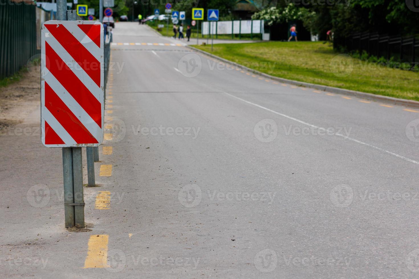 Panneau à rayures diagonales rouge et blanc à l'extrémité de la clôture de la route photo