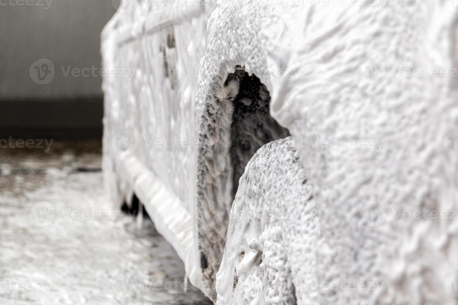 une voiture recouverte de mousse de savon lors du lavage à l'intérieur - gros plan avec mise au point sélective photo