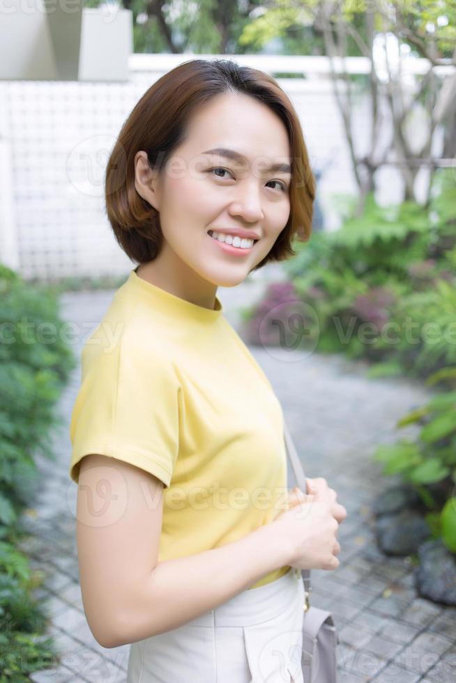 une femme asiatique aux cheveux courts dorés porte un t-shirt à manches courtes de couleur jaune. photo