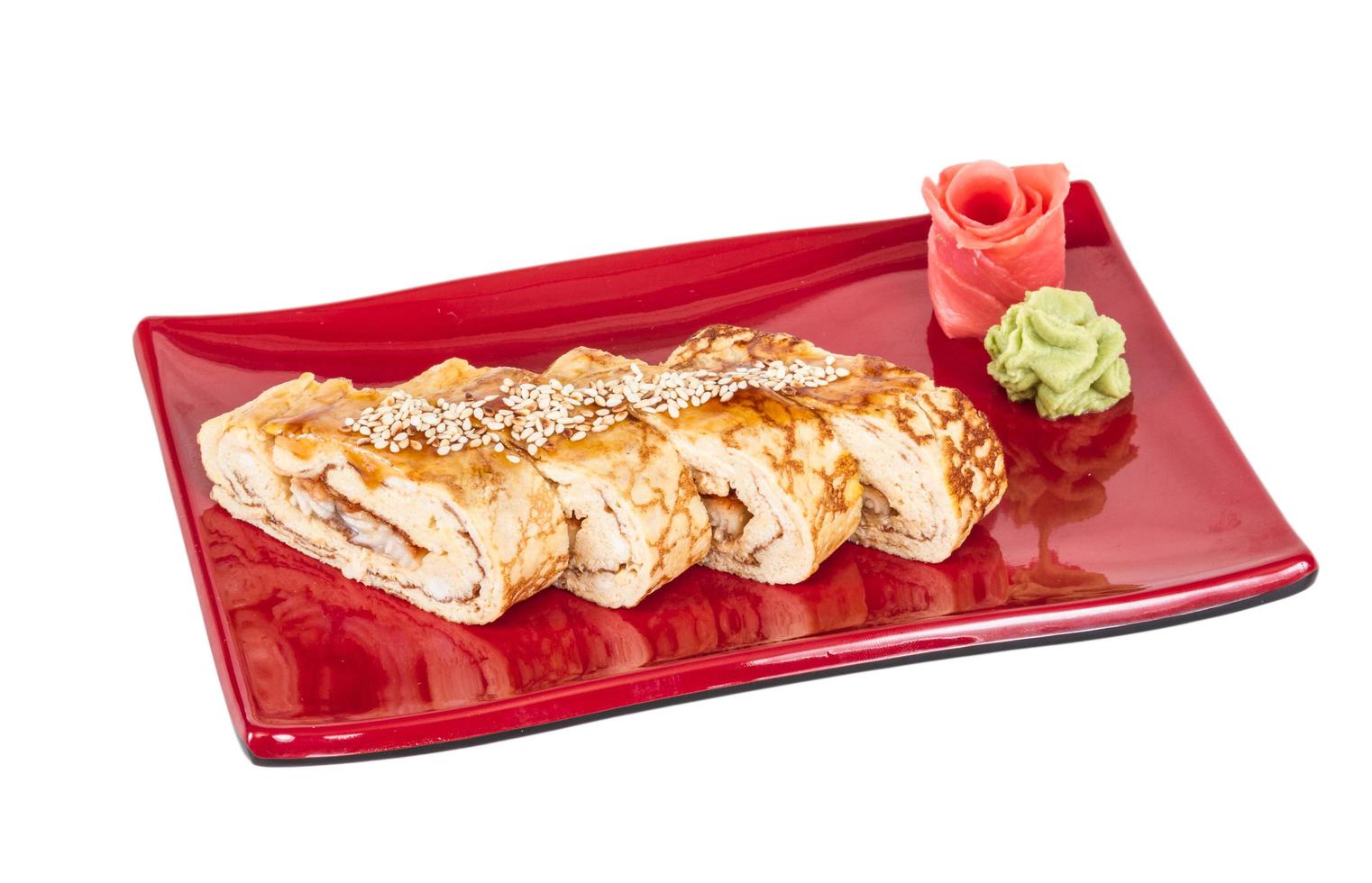 omelette maki sushi - rouleau d'anguille fumée à l'intérieur. garni d'omelette japonaise et de sauce photo