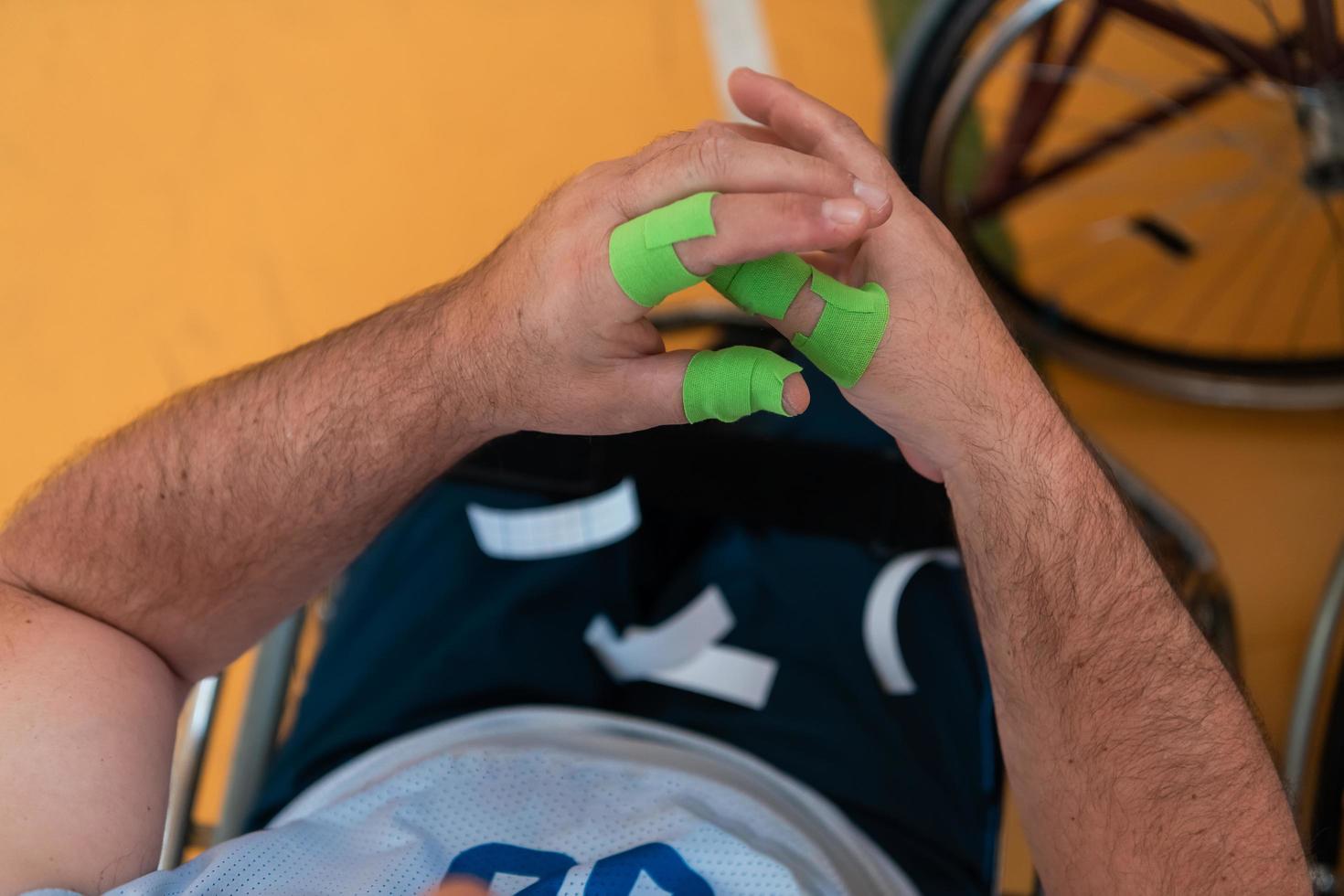 un basketteur handicapé met un corset et des bandages sur ses bras et ses doigts en vue d'un match dans l'arène photo