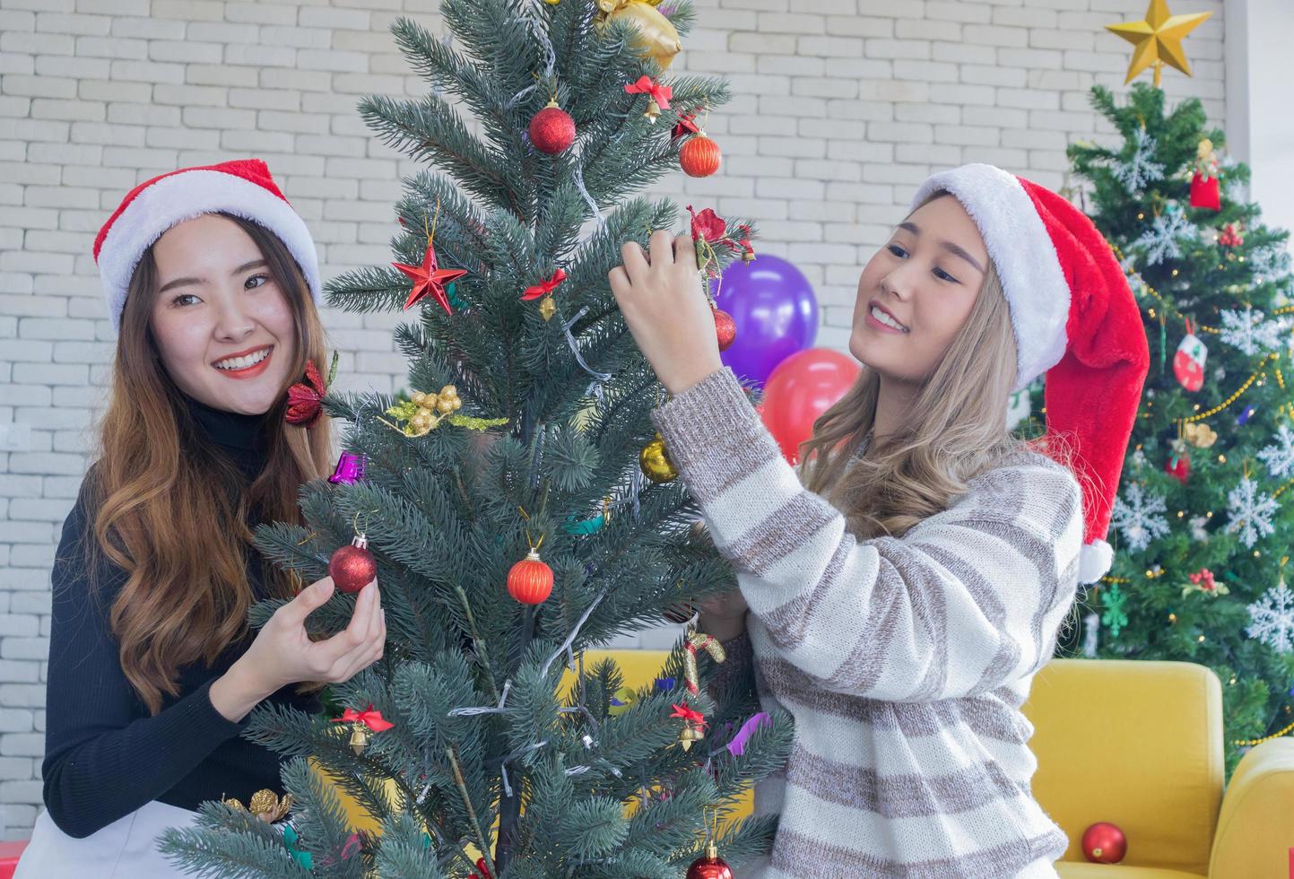 deux femmes décorant un arbre de noël photo