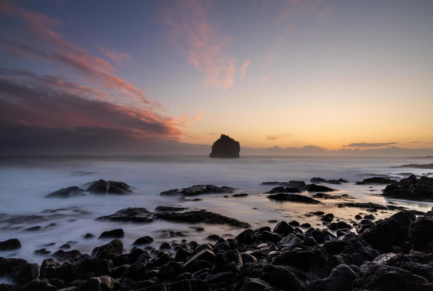 roches noires sur le bord de mer au coucher du soleil photo