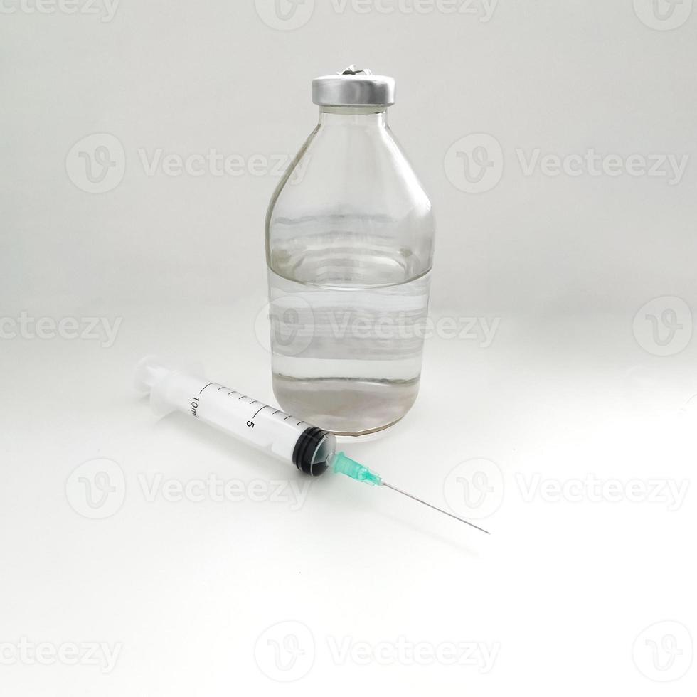 seringue jetable médicale avec aiguille près d'une bouteille en verre avec une solution saline photo
