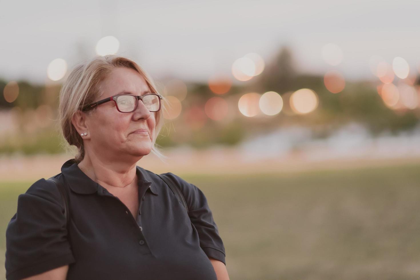 portrait d'une femme âgée aux cheveux blonds et lunettes sur les plages de la mer méditerranée au coucher du soleil. mise au point sélective photo