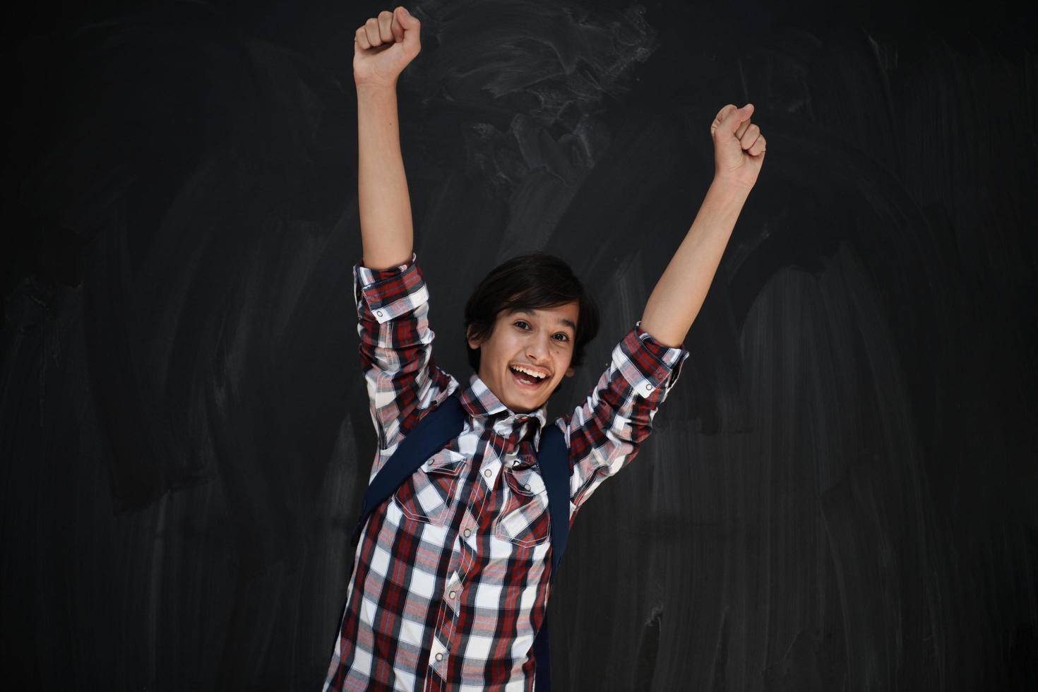 heureux adolescent arabe célébrant contre le tableau noir photo