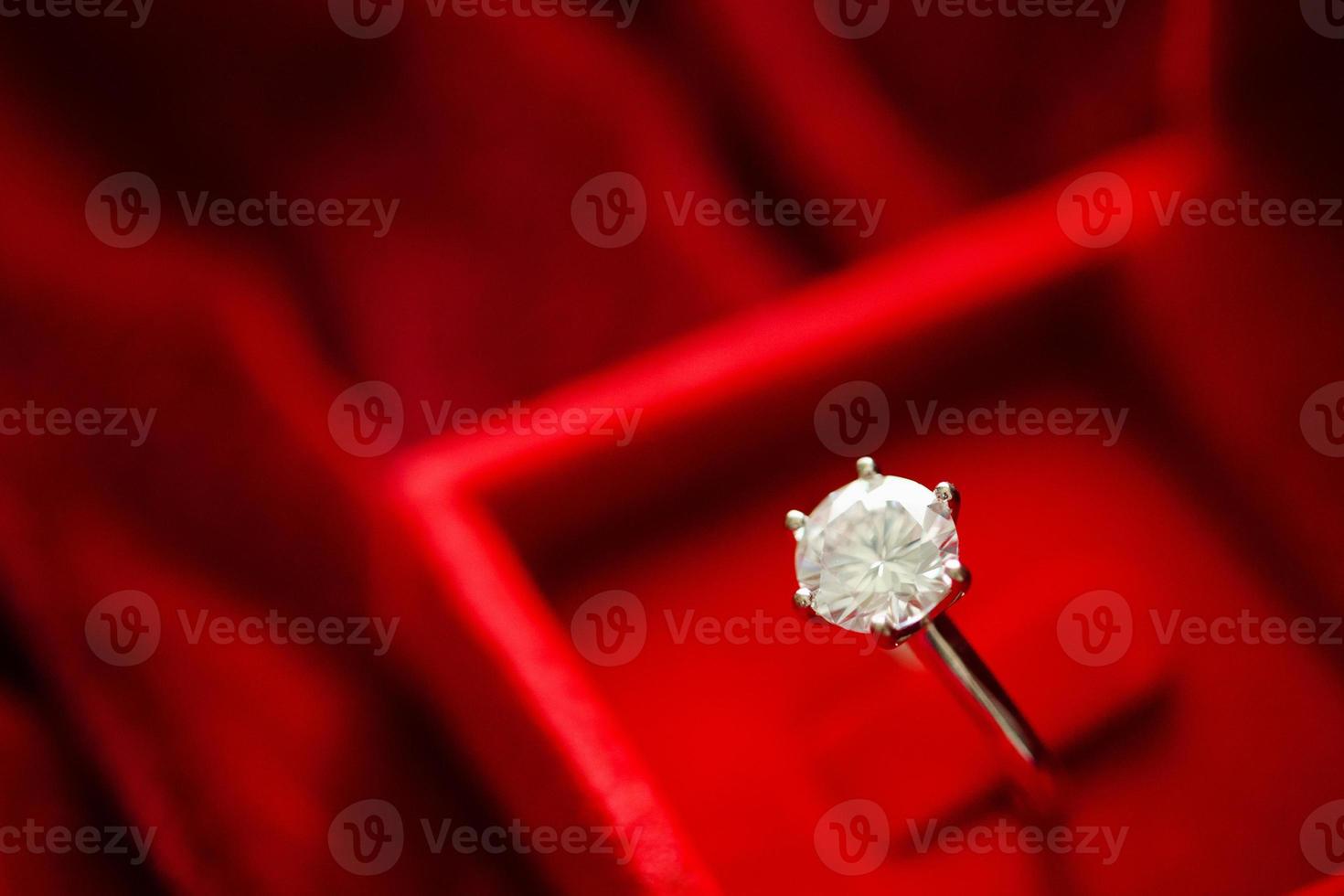 bague en diamant dans une boîte cadeau de bijoux sur fond de tissu rouge photo