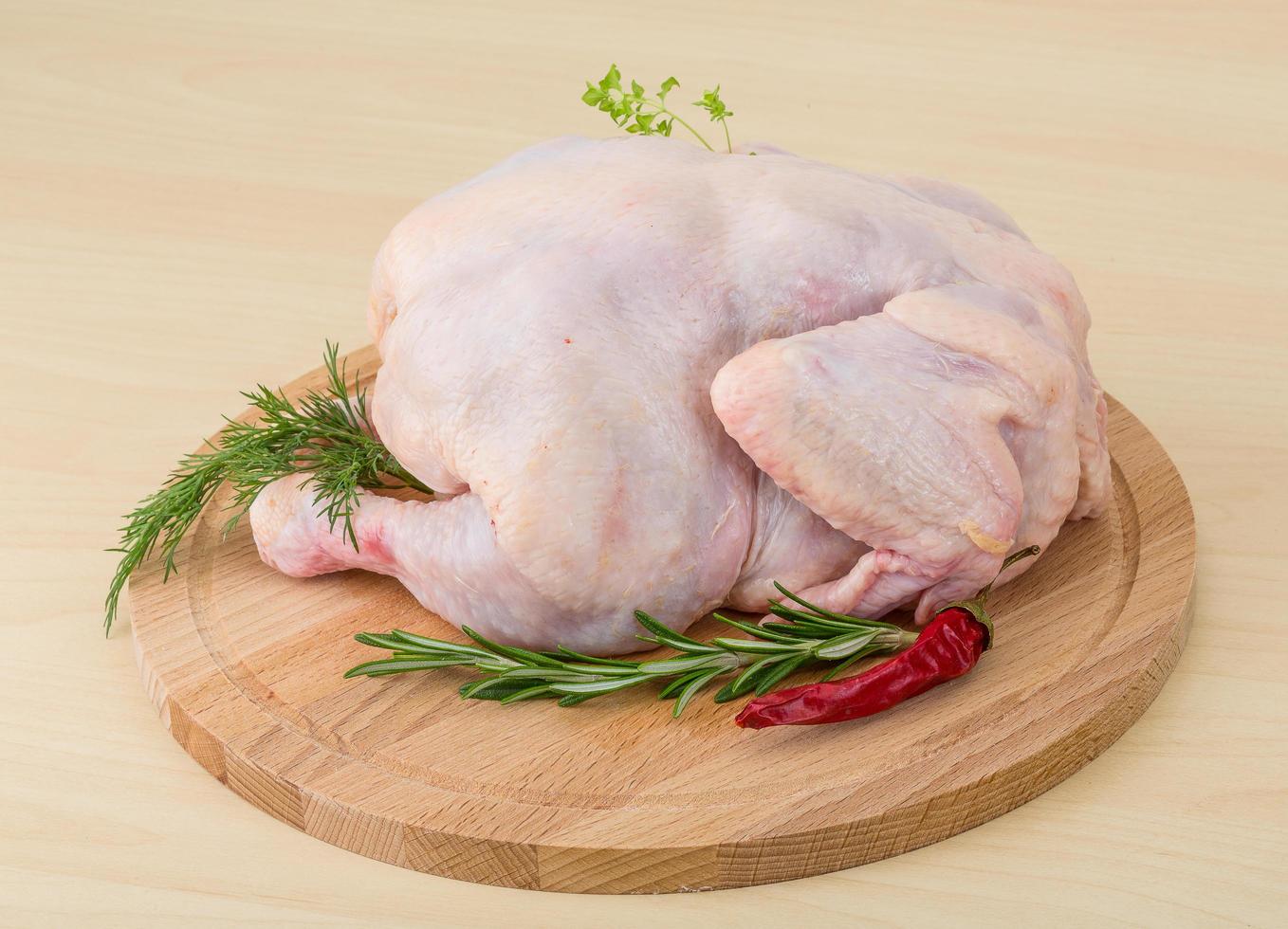 poulet cru sur planche de bois et fond en bois photo