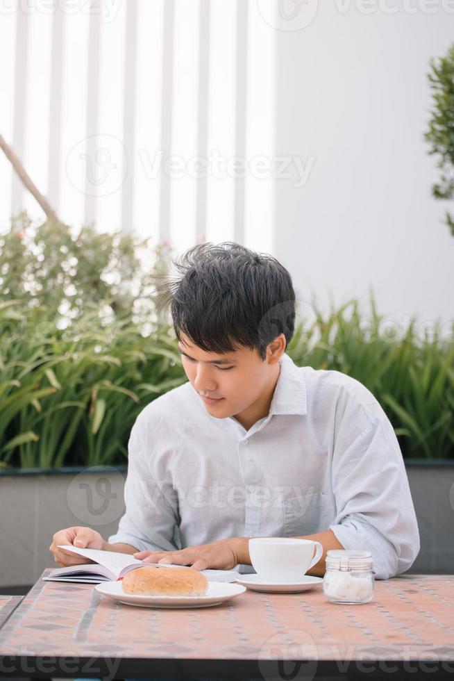 portrait d'un bel homme lisant un livre et appréciant son café. photo