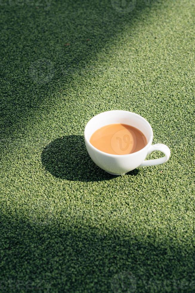 une tasse de café chaud un matin froid, sur l'herbe verte avec fond de rosée photo