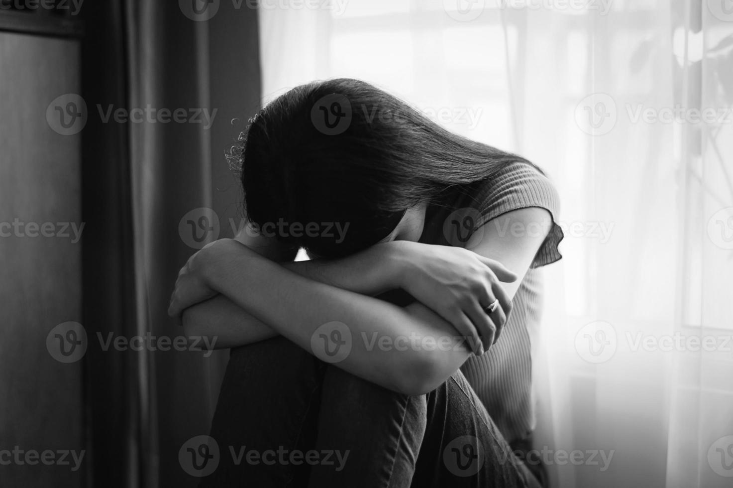 femme assise dépression debout près de la fenêtre et anxiété photo