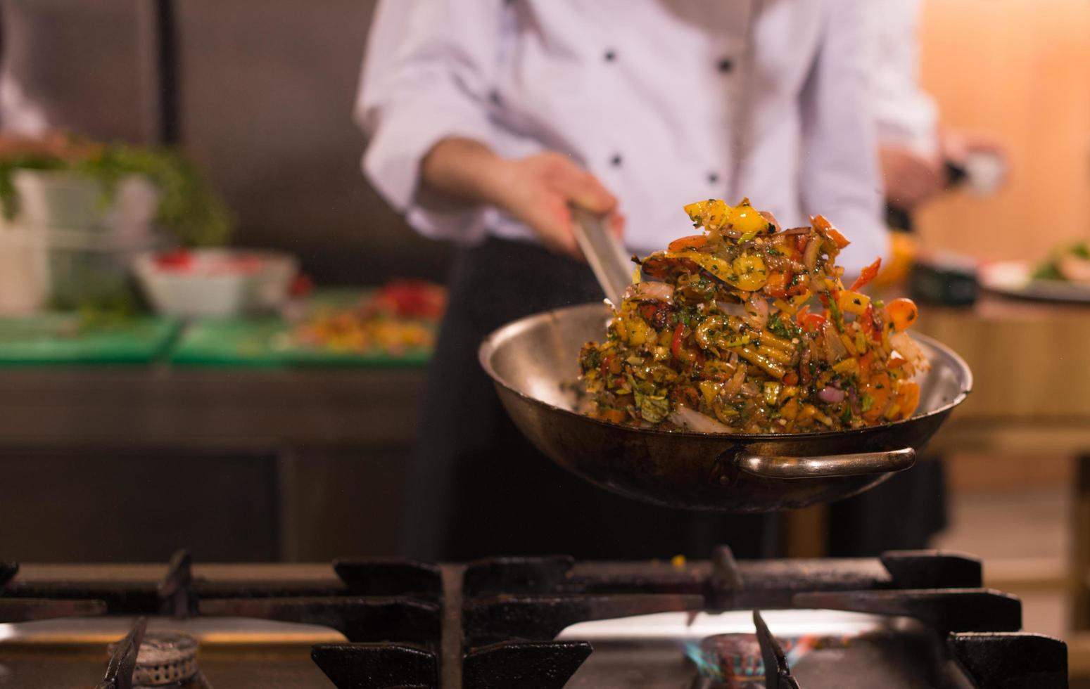 chef retournant les légumes au wok photo