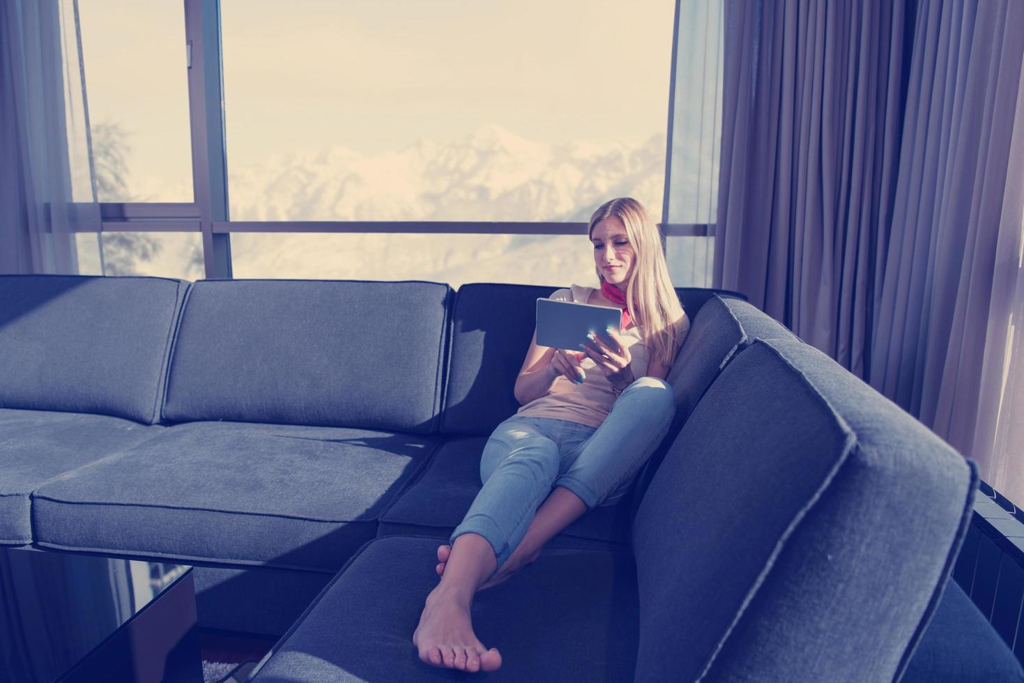 jeune femme sur un canapé à la maison surfant sur le web photo