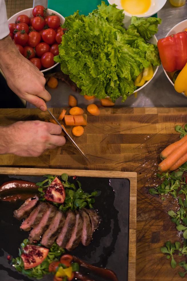 vue de dessus des mains du chef préparant un steak de boeuf photo