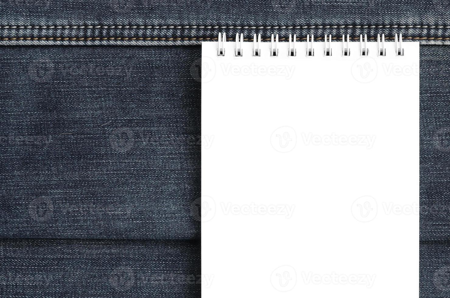 cahier blanc avec des pages propres se trouvant sur fond de jeans bleu foncé. image avec espace de copie photo