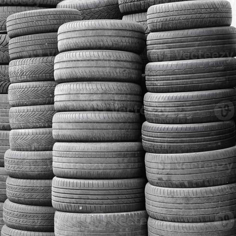 Vieux pneus usagés empilés avec des pieux élevés dans le garage de l'atelier de pièces de voiture secondaire photo