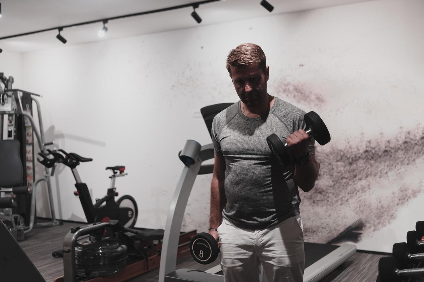 aux prises avec l'âge. homme âgé confiant faisant de l'exercice avec des haltères dans un club de santé. mise au point sélective photo