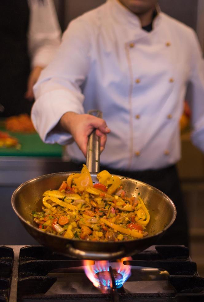 chef retournant les légumes au wok photo