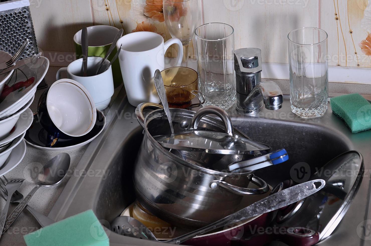 un énorme tas de vaisselle non lavée dans l'évier de la cuisine et sur le comptoir photo