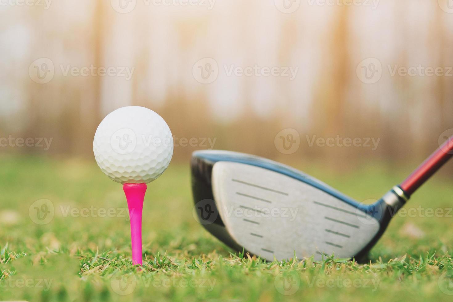 le club de golf et la balle de golf se bouchent dans un champ d'herbe avec le coucher du soleil et le beau temps du soir. photo