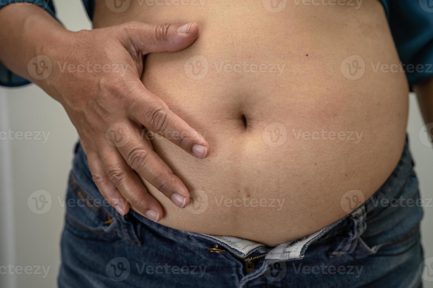 une femme asiatique en surpoids montre un gros ventre au bureau. photo