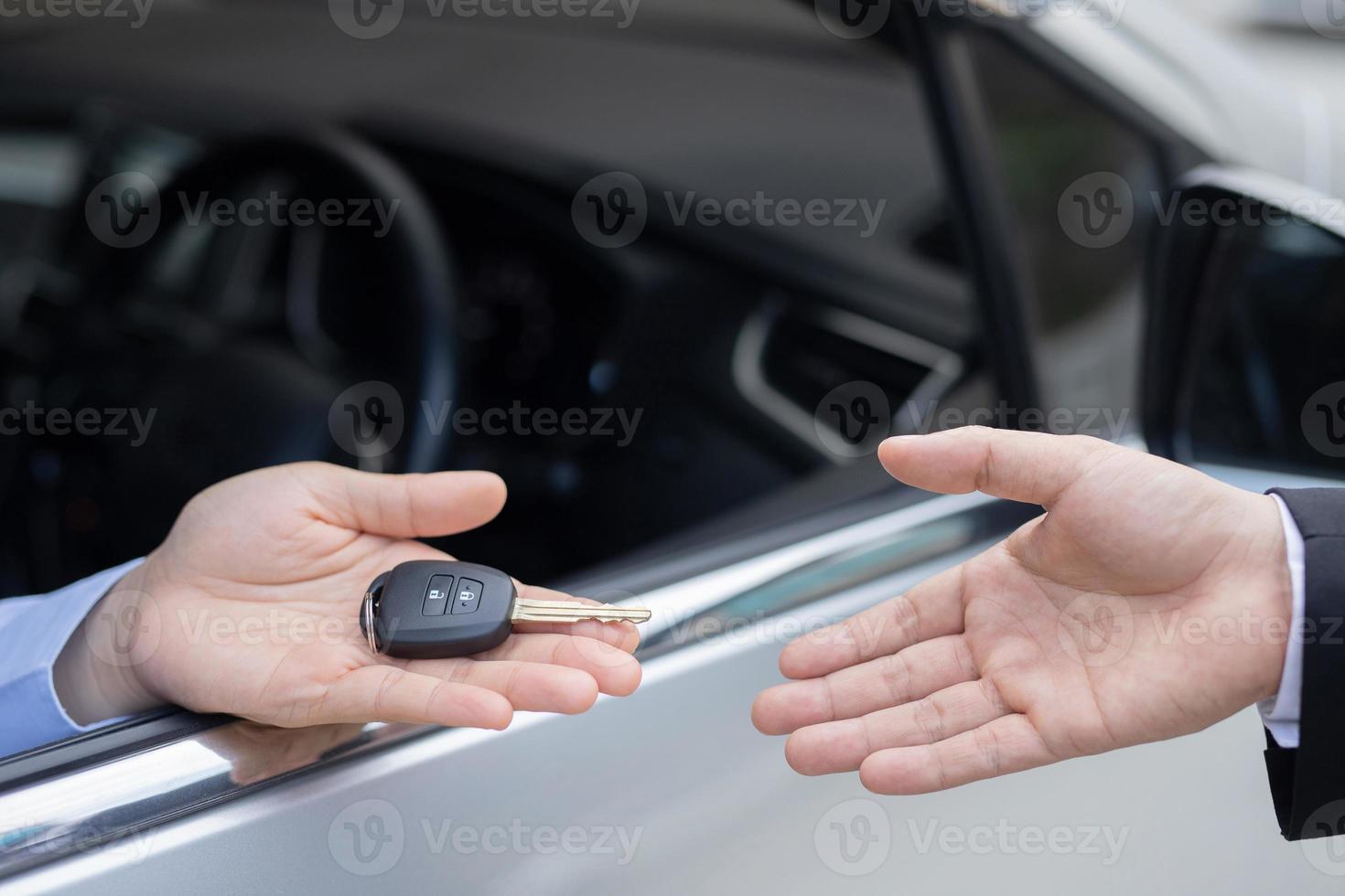 le vendeur porte les clés de voiture livrées au client dans la salle d'exposition avec une offre à faible intérêt. promotion spéciale photo