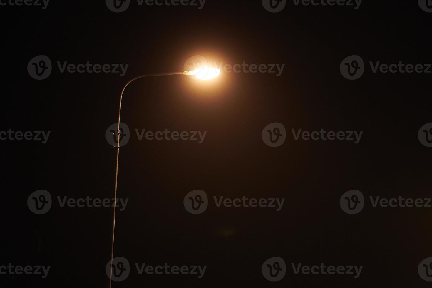 un lampadaire de nuit brille d'une faible lumière jaune mystérieuse à travers le brouillard du soir, espace de copie photo