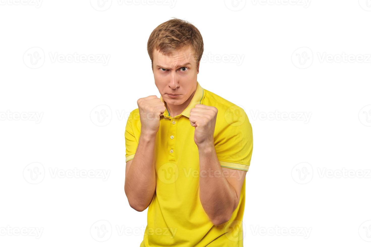 Jeune homme en colère en t-shirt jaune prêt à se battre avec les poings isolé sur fond blanc photo