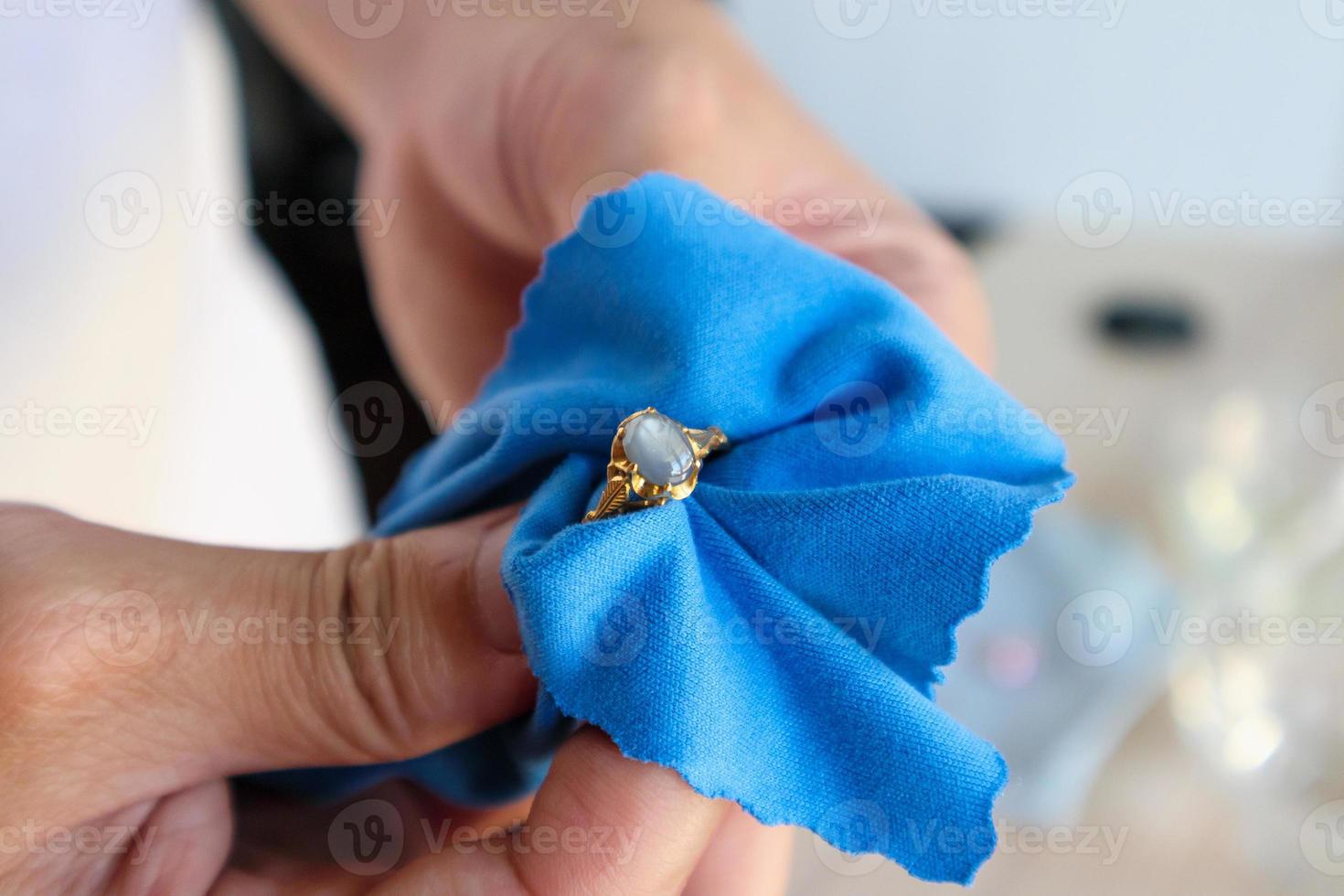 Bijoutier polissant et nettoyant à la main une bague de bijoux en or avec un tissu en microfibre photo