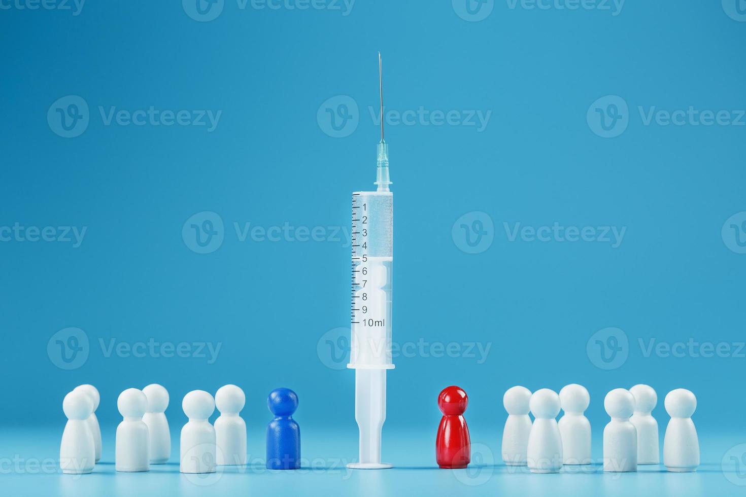 une seringue avec un vaccin au centre avec un homme bleu et rouge avec une foule de blancs sur fond bleu. photo