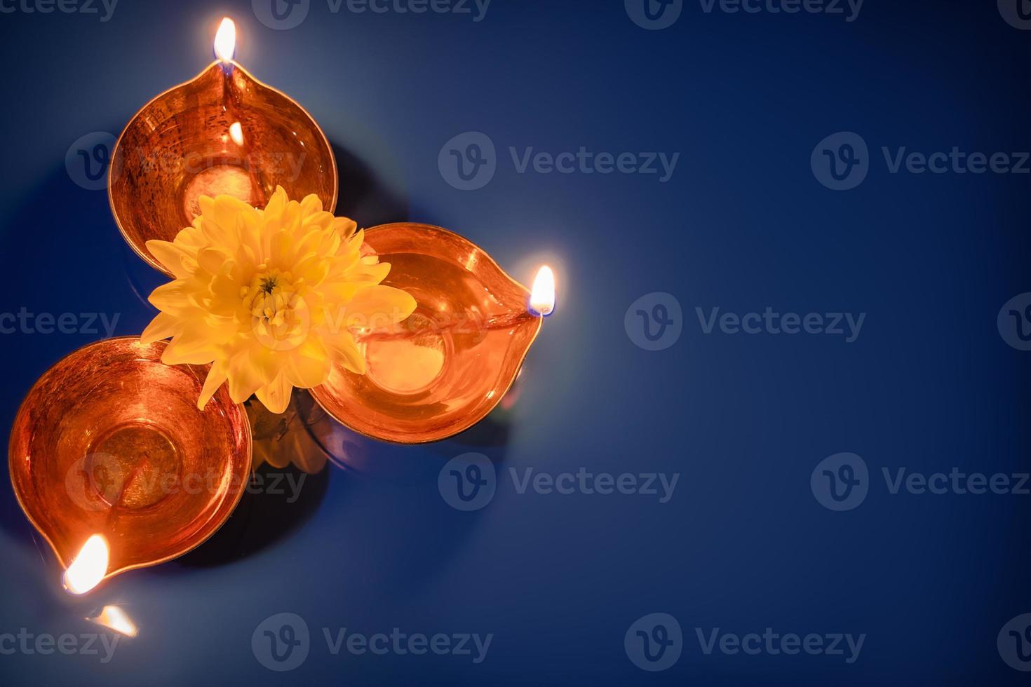 joyeux Diwali. lampes à huile diya et fleurs jaunes sur fond bleu. célébrant la traditionnelle fête indienne de la lumière. photo
