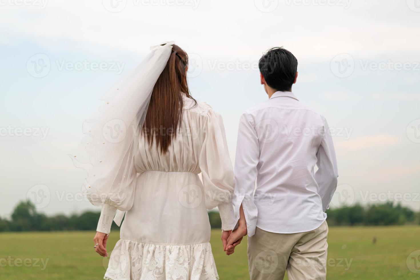 heureux jeune couple asiatique en vêtements de mariée et de marié photo