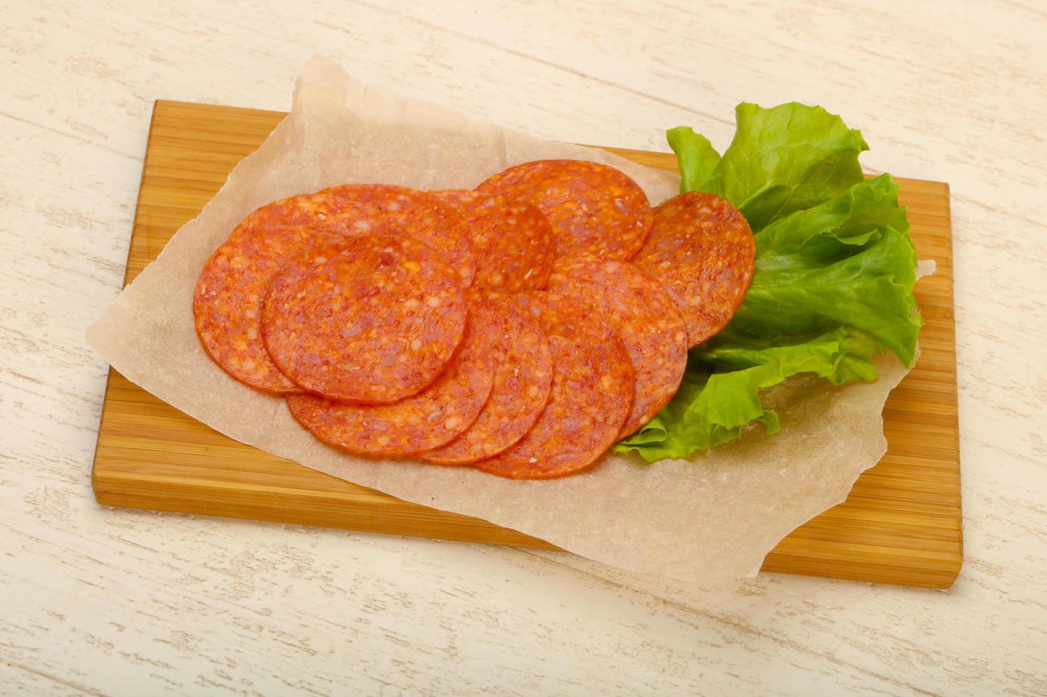 Saucisse au pepperoni sur planche de bois et fond de bois photo