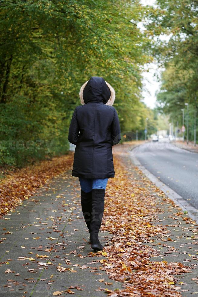 femme méconnaissable portant un manteau d'hiver et des bottes marchant dans la rue photo