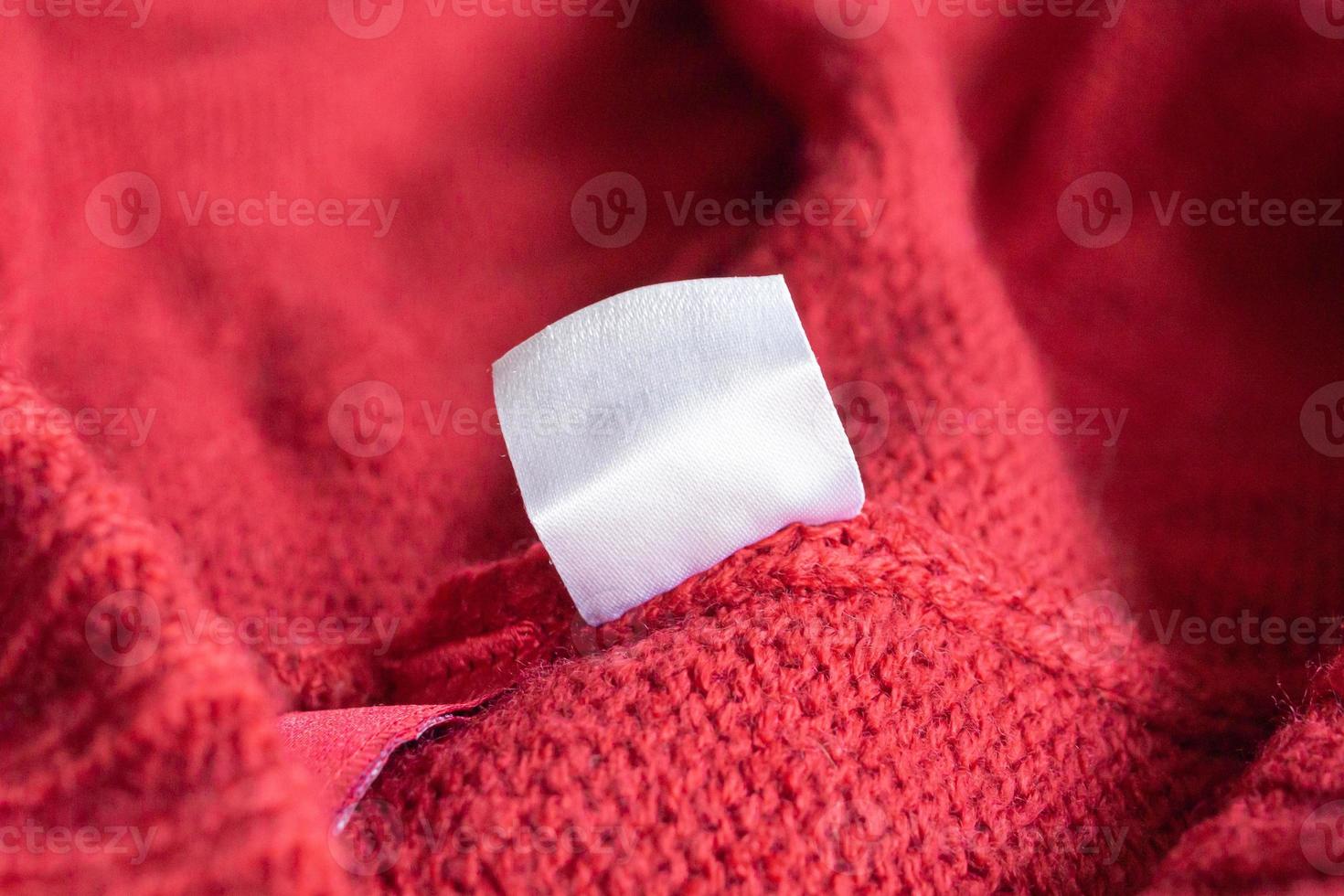 étiquette de vêtements de soin de lessive blanche vierge sur fond de texture tricotée rouge photo