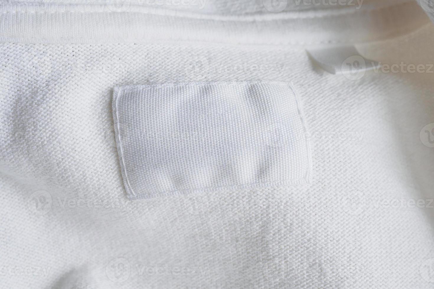 Étiquette de vêtements blancs vierges sur fond de chemise en coton neuf photo