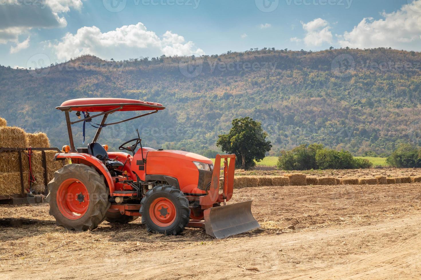tracteur dans le domaine de l'agriculture avec montagne et ciel bleu photo