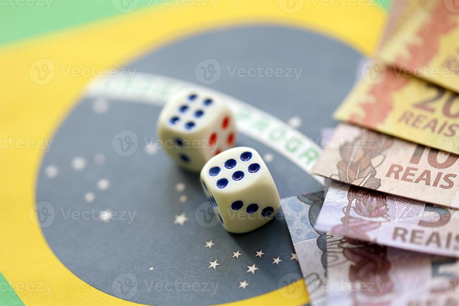 cubes de dés avec des billets d'argent brésiliens sur le drapeau de la république du brésil. concept de chance et de jeu au brésil photo