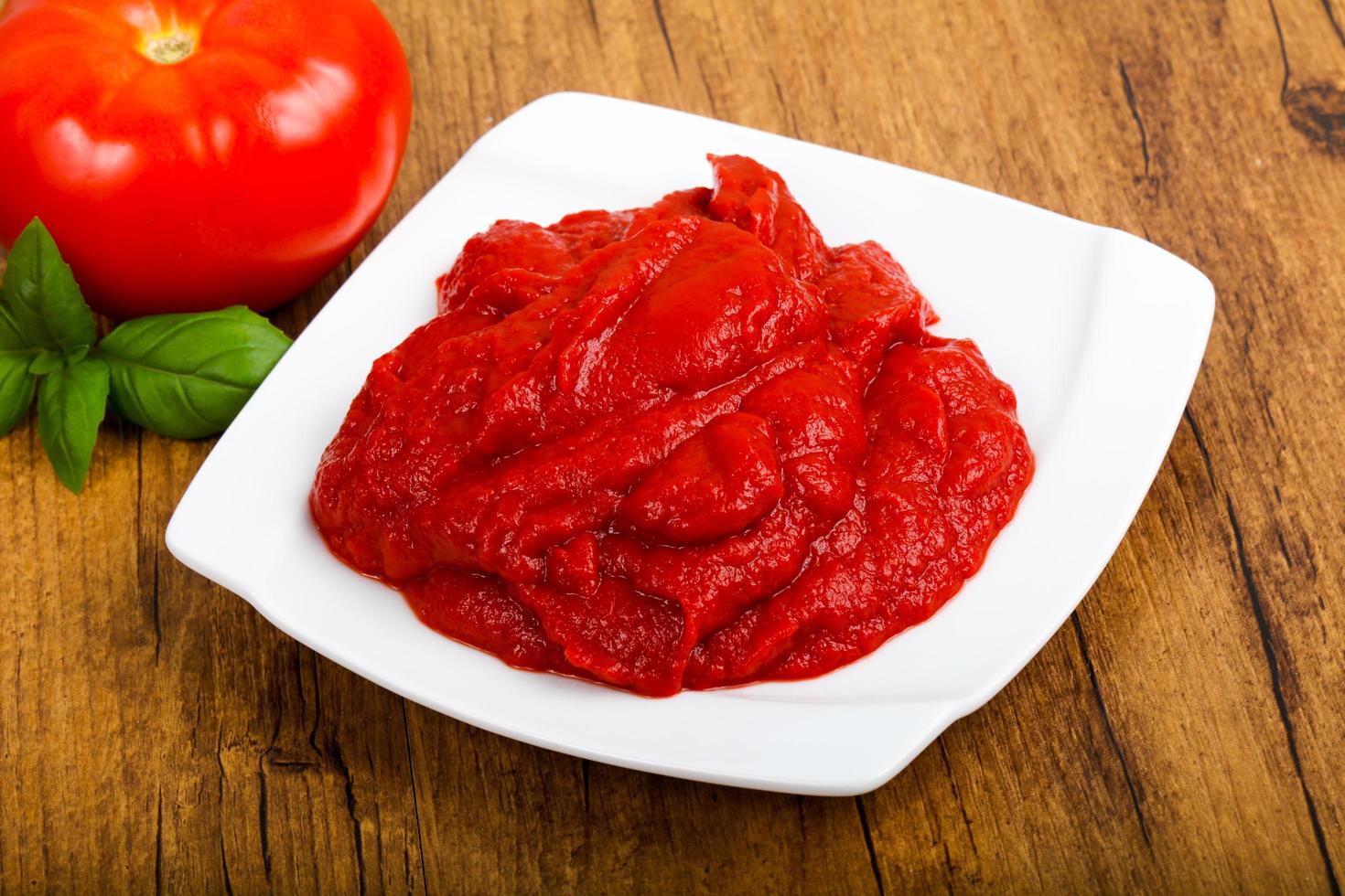 pâte de tomate sur la plaque et fond en bois photo