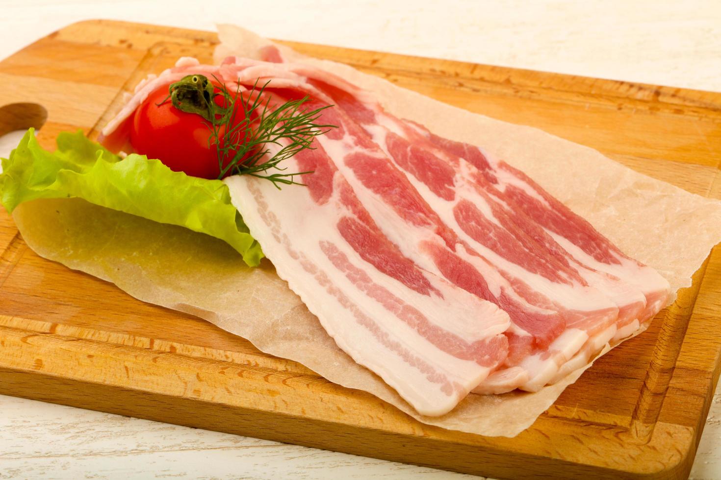 bacon cru sur planche de bois et fond en bois photo