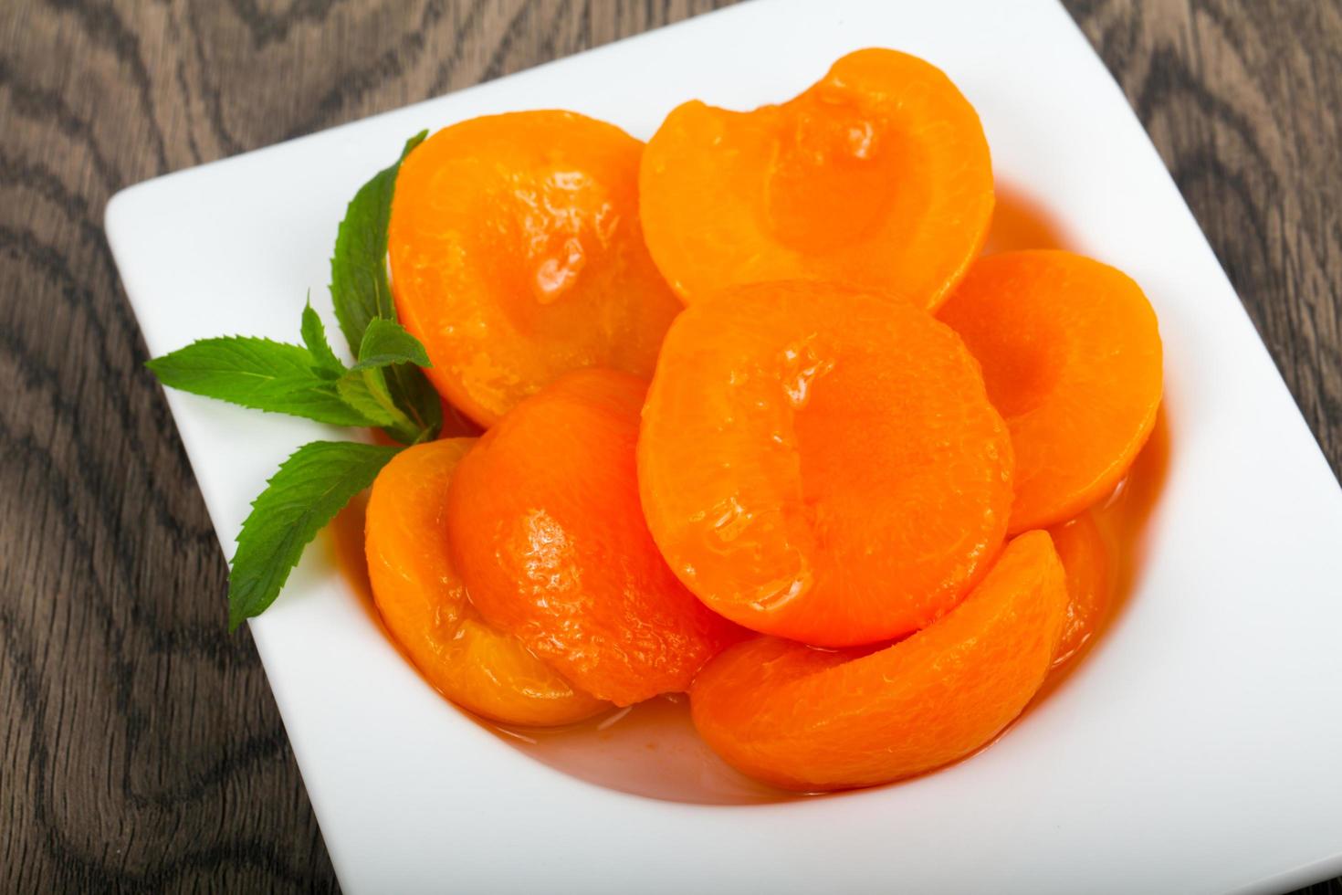 Abricots en conserve dans un bol sur fond de bois photo