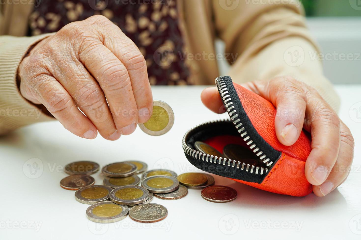 une femme âgée à la retraite comptant des pièces de monnaie et s'inquiète des dépenses mensuelles et du paiement des frais de traitement. photo