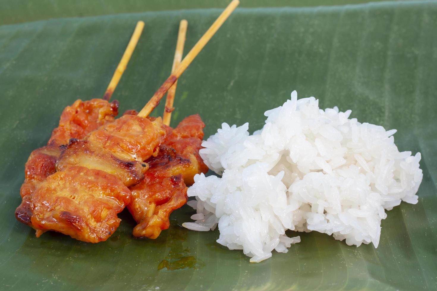 le porc grillé avec du riz gluant sur fond de feuille de bananier est un aliment que les thaïlandais préfèrent manger. photo