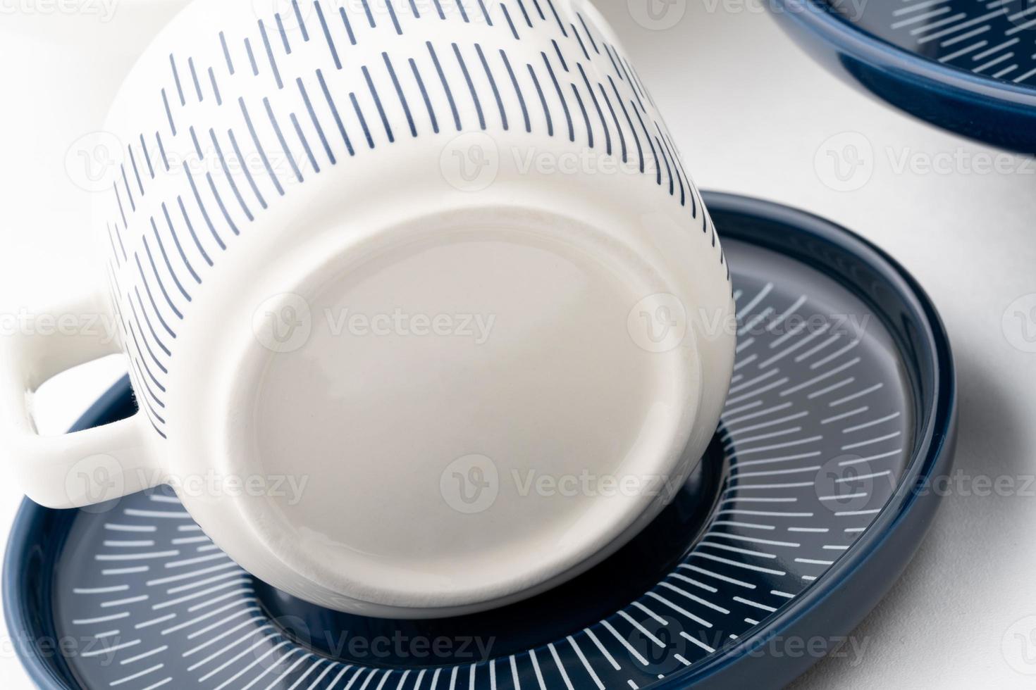 Un gros plan d'un mug bleu et blanc sur une soucoupe avec un fond blanc photo
