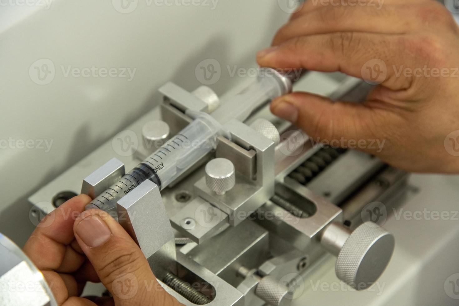 un gros plan de mains travaillant sur une machine dans un entrepôt de production médicale de seringues photo