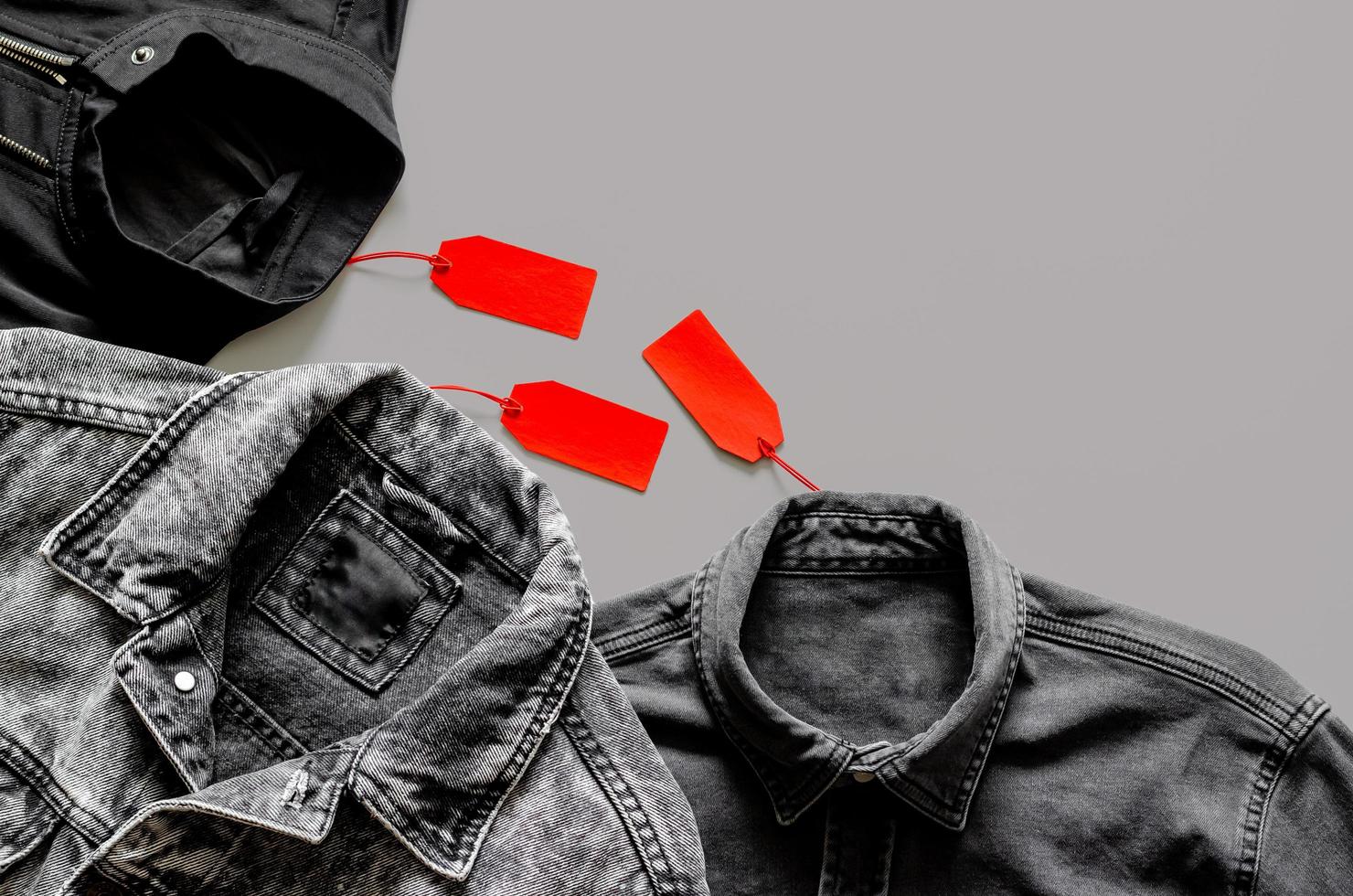 mise à plat d'hommes vêtements noirs avec des étiquettes de prix rouges sur fond gris pour le concept de vente shopping vendredi noir. photo