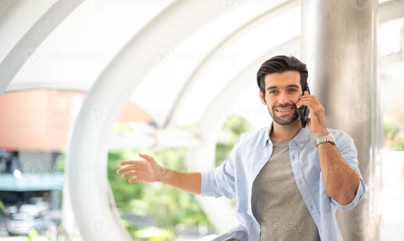 le jeune homme utilisant un smartphone pour parler avec son ami à l'extérieur. l'homme portant un tissu décontracté et se sentant heureux et relaxant. photo